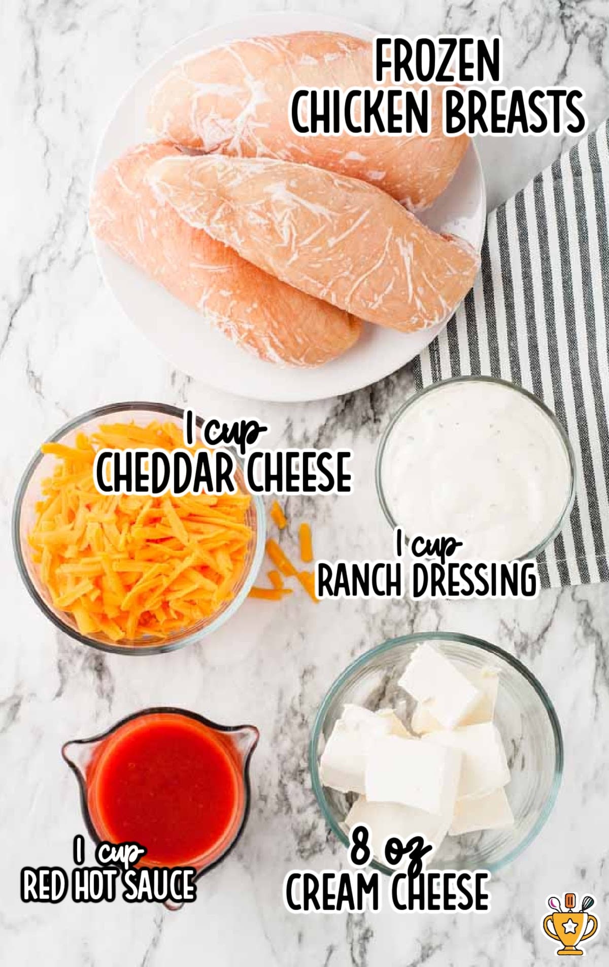 Flat lay of buffalo dip ingredients including frozen chicken, cheddar, ranch, cream cheese, and hot sauce labeled with text.
