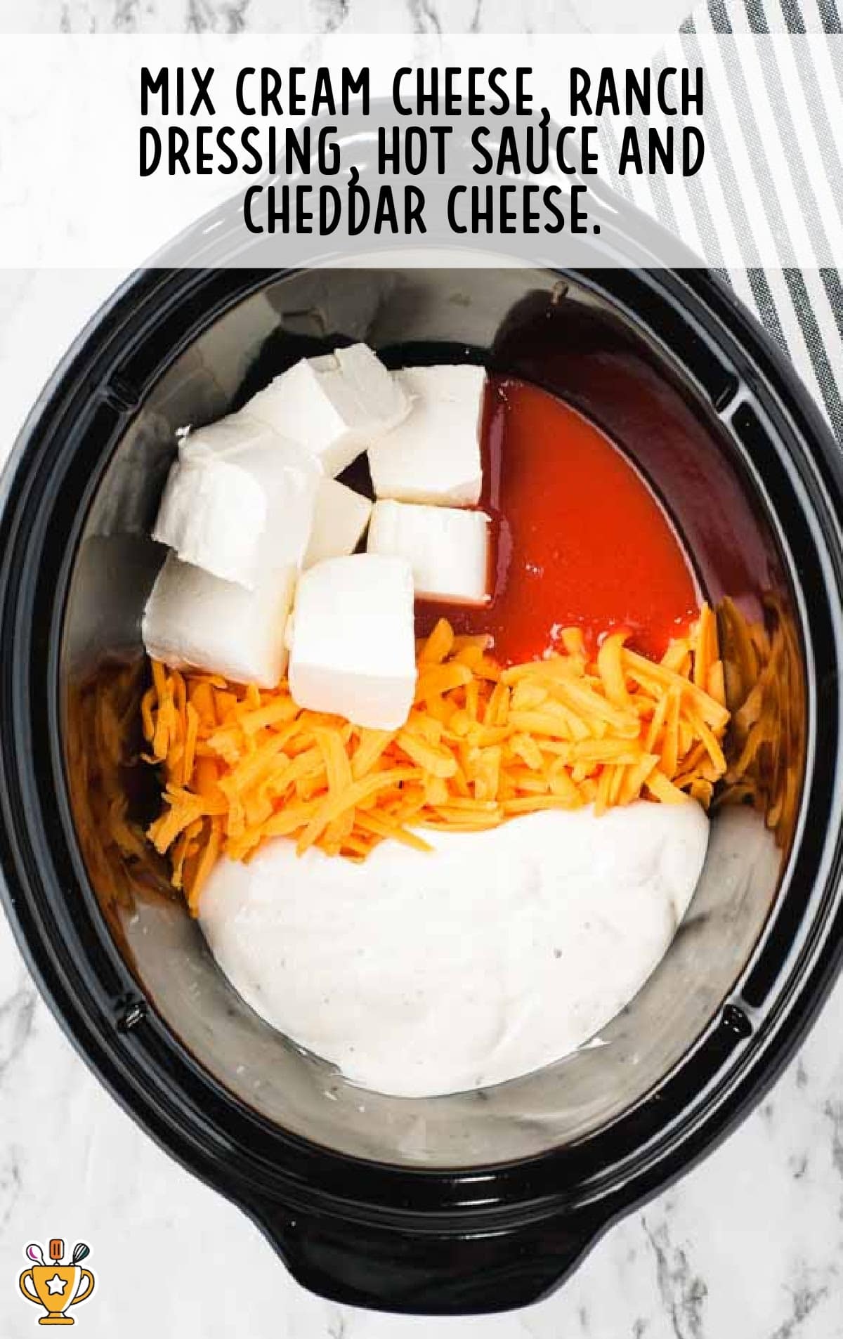 A close-up of a black crockpot filled with cream cheese blocks, shredded cheddar cheese, ranch dressing, and hot sauce before mixing