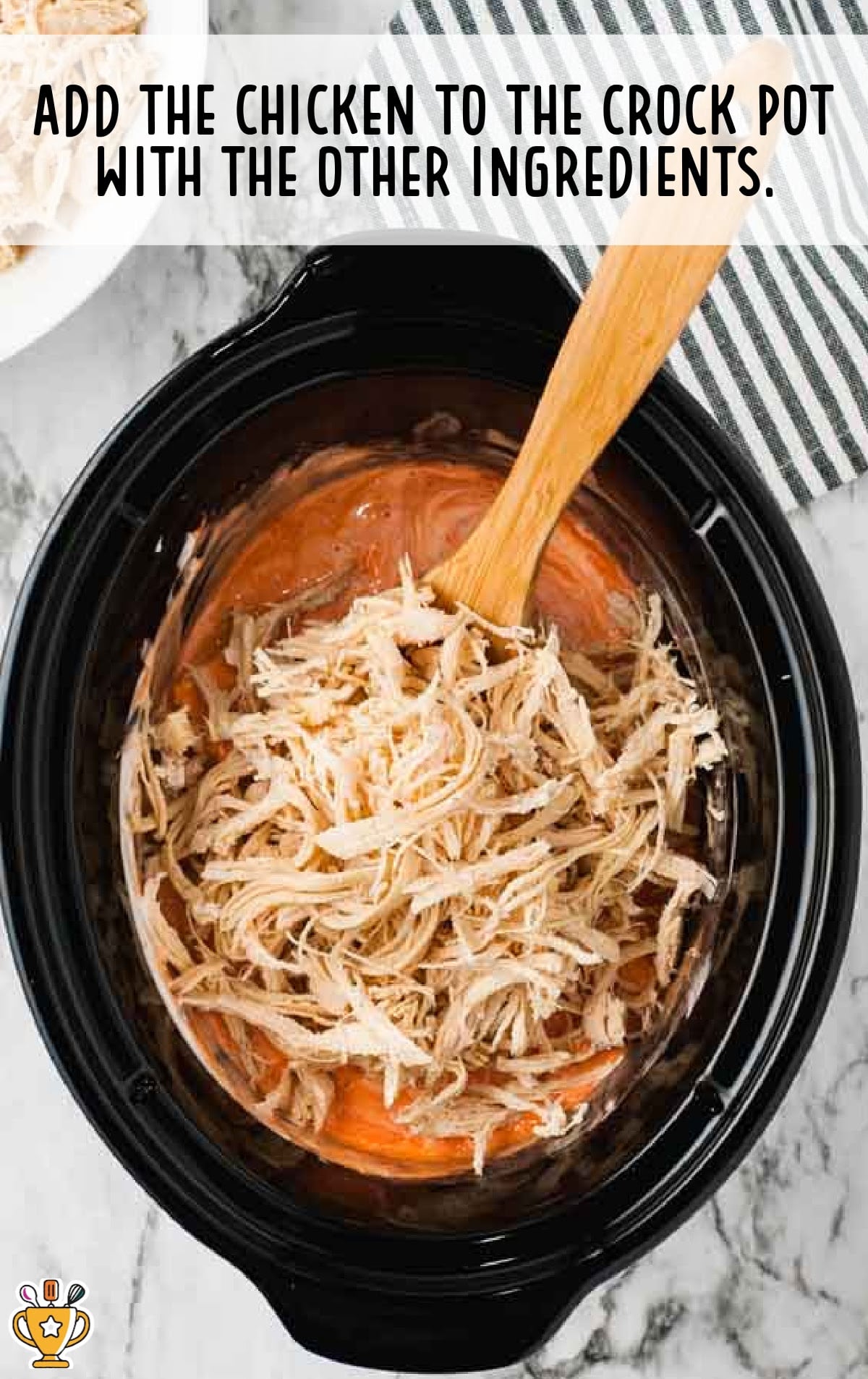 Shredded chicken being added to the crockpot with creamy buffalo mixture already inside, ready to be combined.