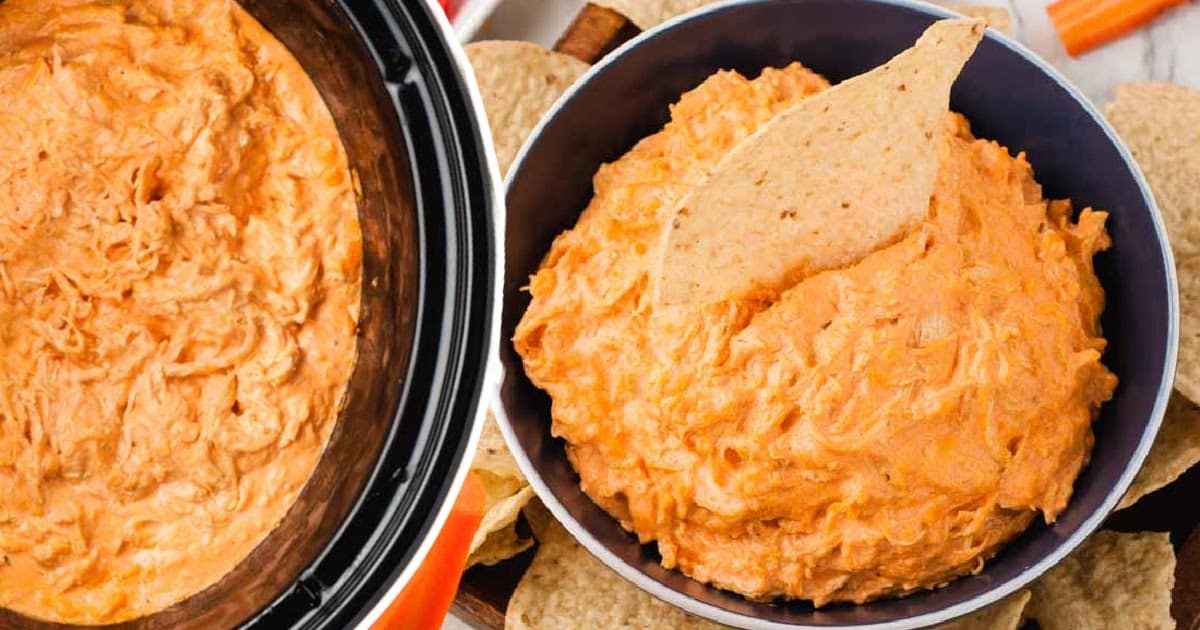 Hand dipping tortilla chip into a bowl of rich, creamy buffalo chicken dip with a smooth texture.