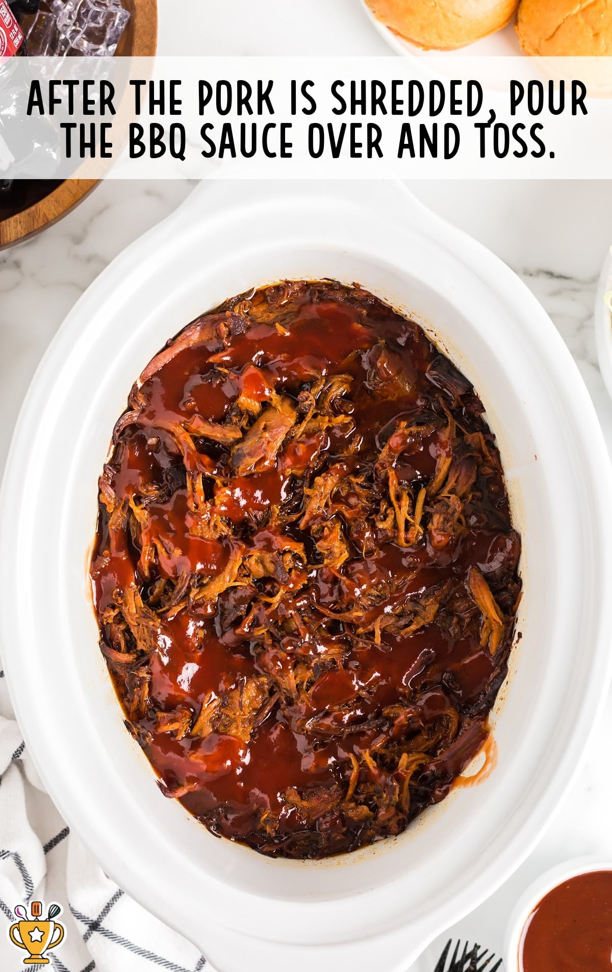 Shredded pork in crockpot topped with barbecue sauce, ready to be tossed and served after cooking.