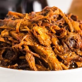 Bowl filled with juicy, shredded Dr. Pepper Pulled Pork in rich barbecue sauce, perfect for sandwiches or summer gatherings.