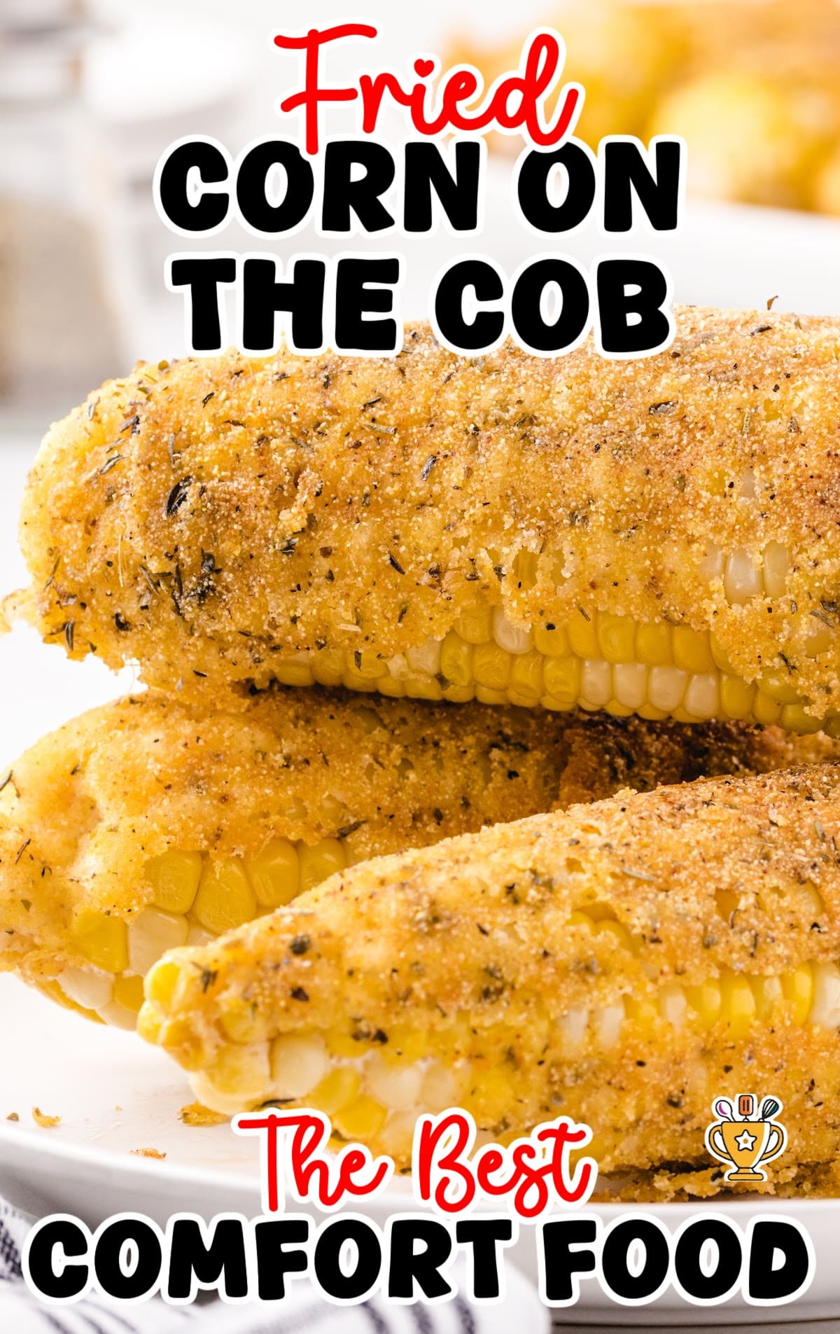 Close-up of crispy fried corn on the cob stacked on a plate, seasoned with spices and herbs.