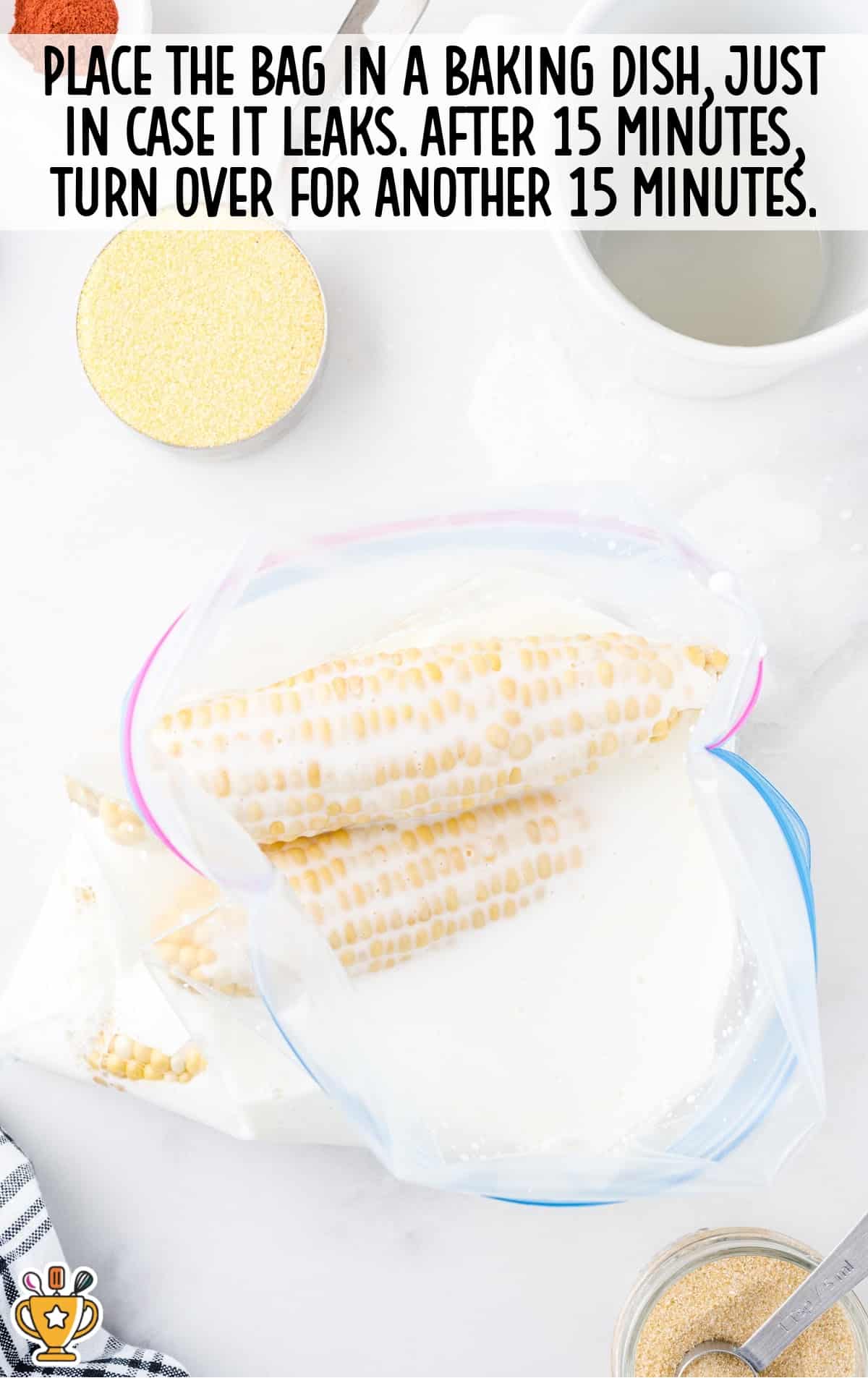 Ziploc bag with corn soaking in buttermilk inside a baking dish for marinating.