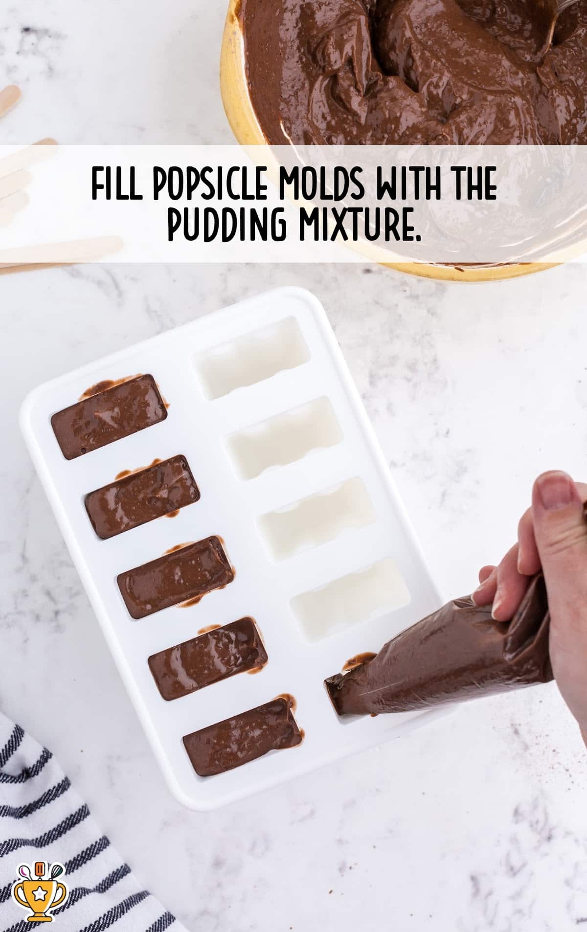 Pudding mixture being piped into popsicle molds, half filled, with a hand holding the bag.