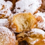 Square image of golden funnel cake bites dusted in powdered sugar, highlighting the texture of the fried dough and soft inside.