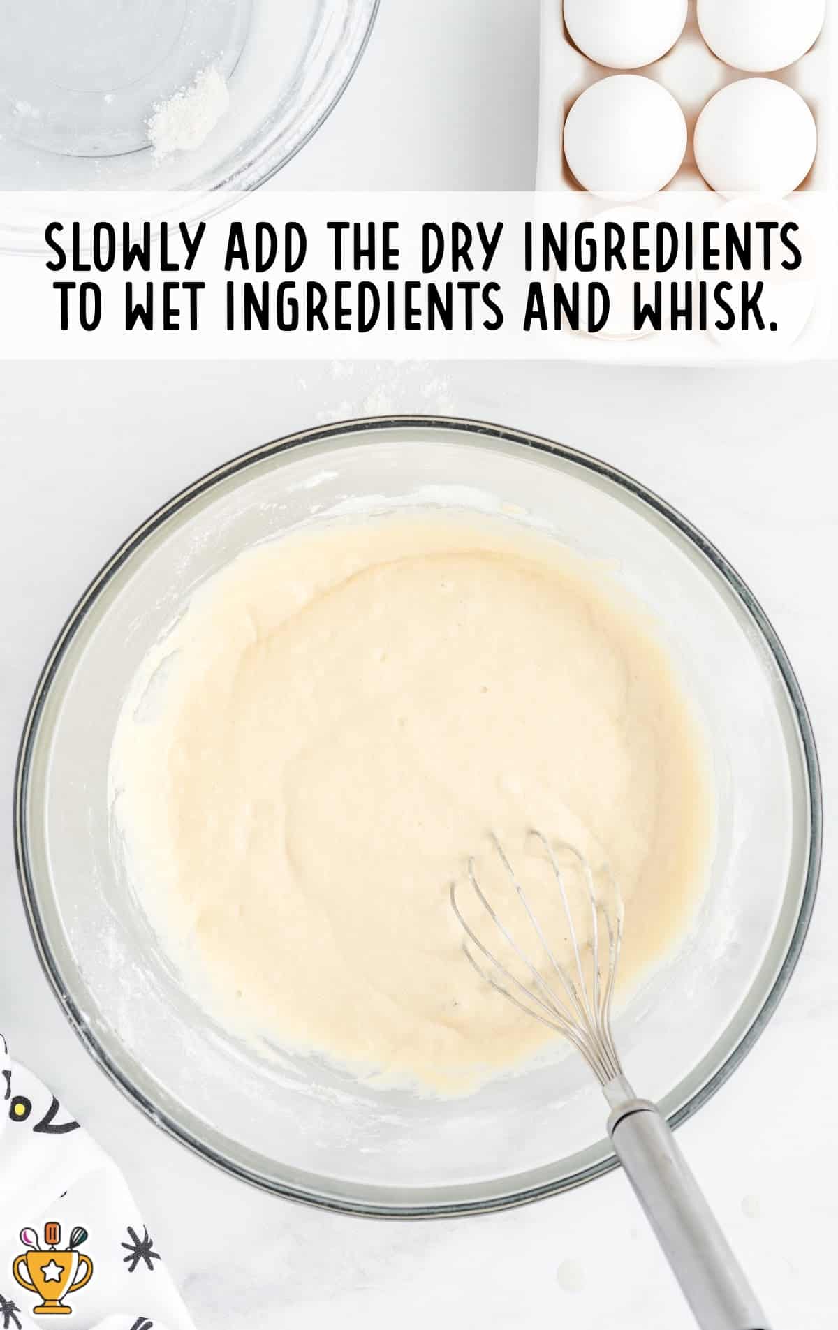 Mixed wet ingredients in a glass bowl after whisking, ready for dry ingredients to be added.