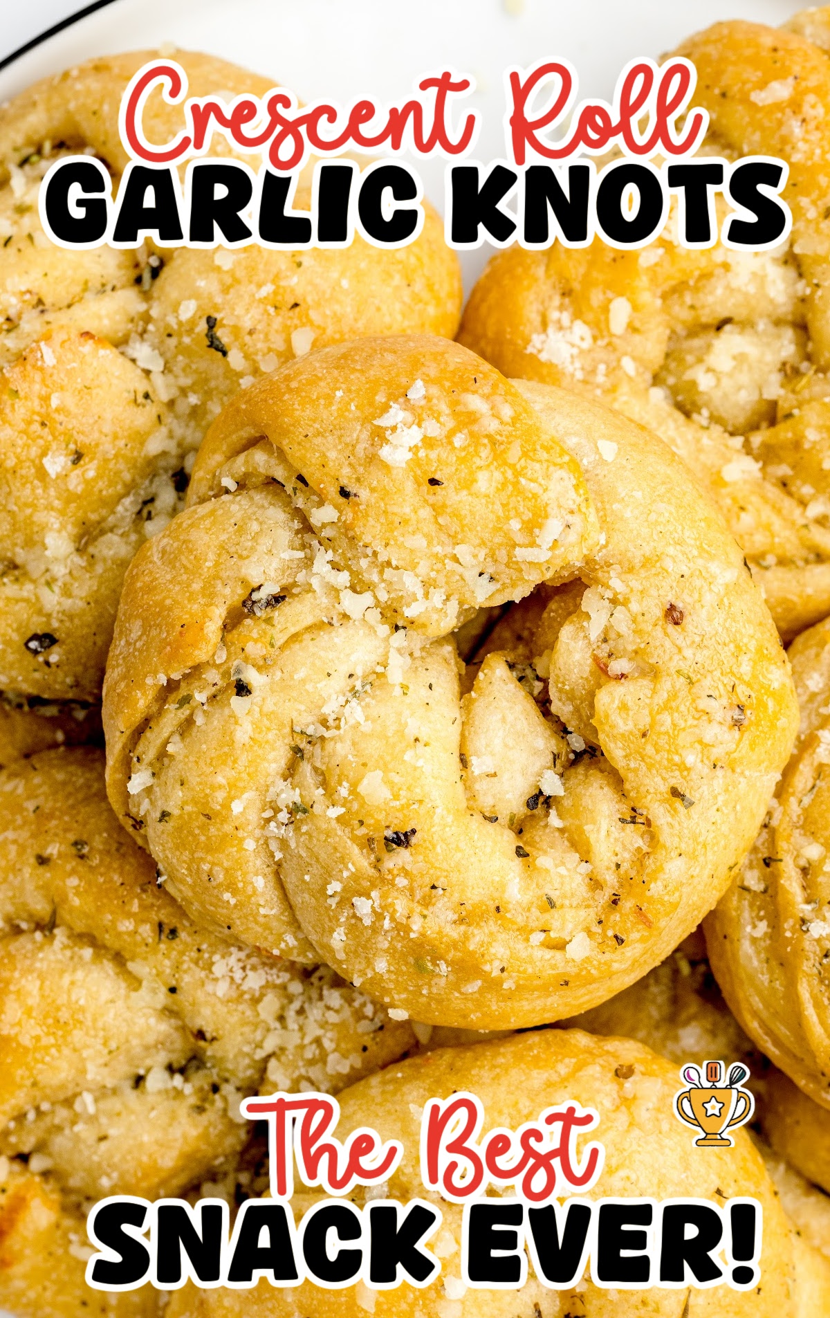 Stack of garlic knots topped with herbs and Parmesan on a white plate.