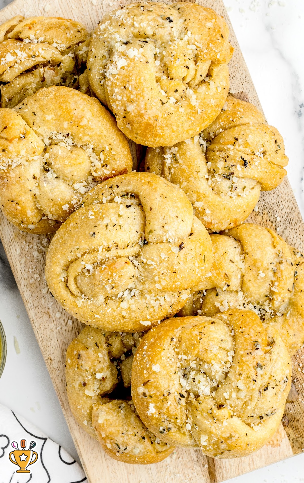 Garlic knot with gooey melted cheese pulling apart on parchment paper.