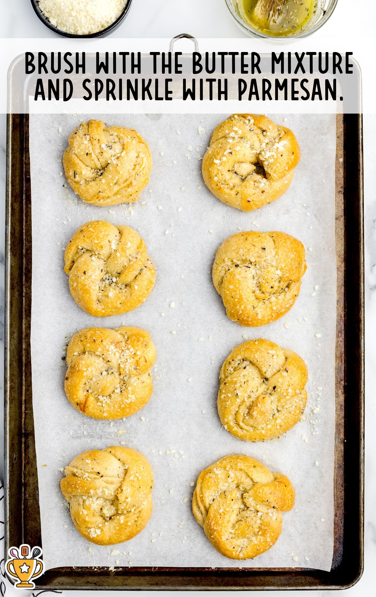 Eight garlic knots baked on a sheet pan and brushed with butter.