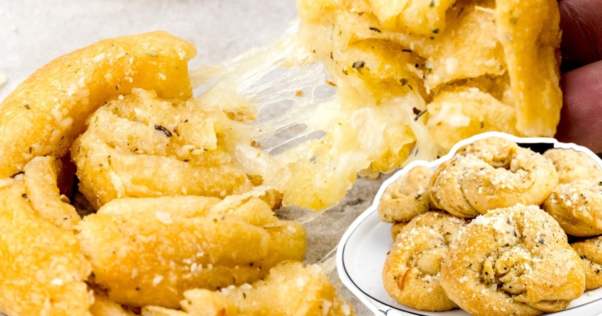 Cheesy garlic knot being pulled apart with melted cheese stretching inside.
