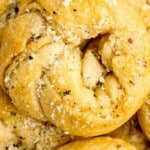 Close-up of baked garlic knots with parmesan sprinkled on top and text that reads “The Best Snack Ever!”