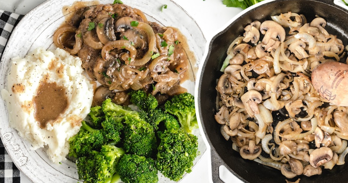Top-down view of a plate with hamburger steak, broccoli, and mashed potatoes next to a skillet filled with saut&eacute;ed mushrooms and onions.