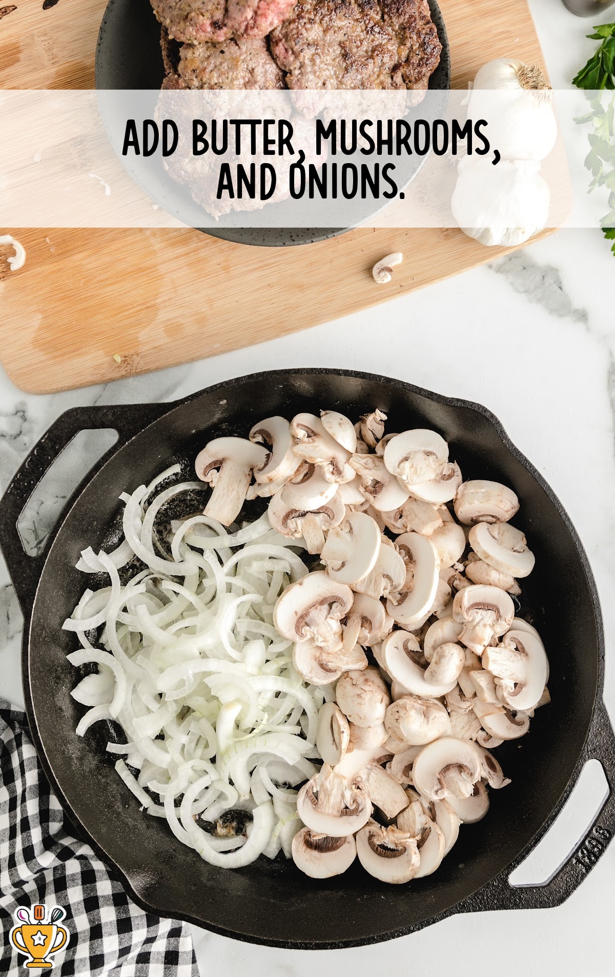 Cast iron skillet filled with raw sliced onions and mushrooms cooking in butter, ready to be saut&eacute;ed.
