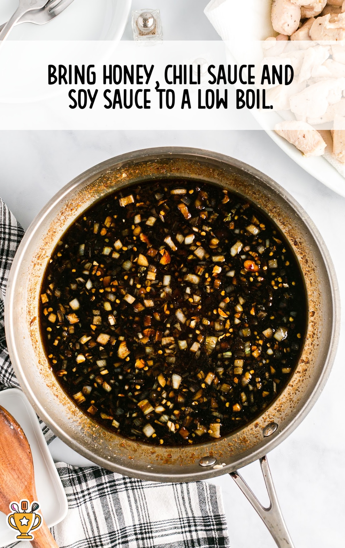 Dark sauce mixture with visible onions and spices in a skillet, being brought to a low boil for the chicken.