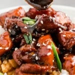 Vertical pin image showing honey garlic chicken plated with rice, sesame seeds, and scallions, with a bold text that reads "Honey Garlic Chicken - Better Than Takeout!"