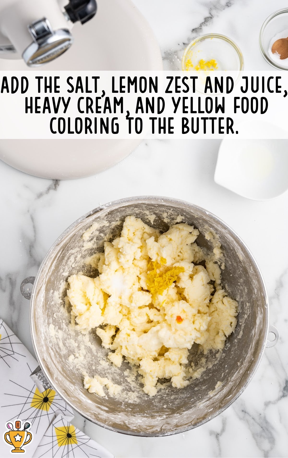 Salt, lemon zest, lemon juice, heavy cream, and food coloring added to the butter mixture in the mixing bowl.
