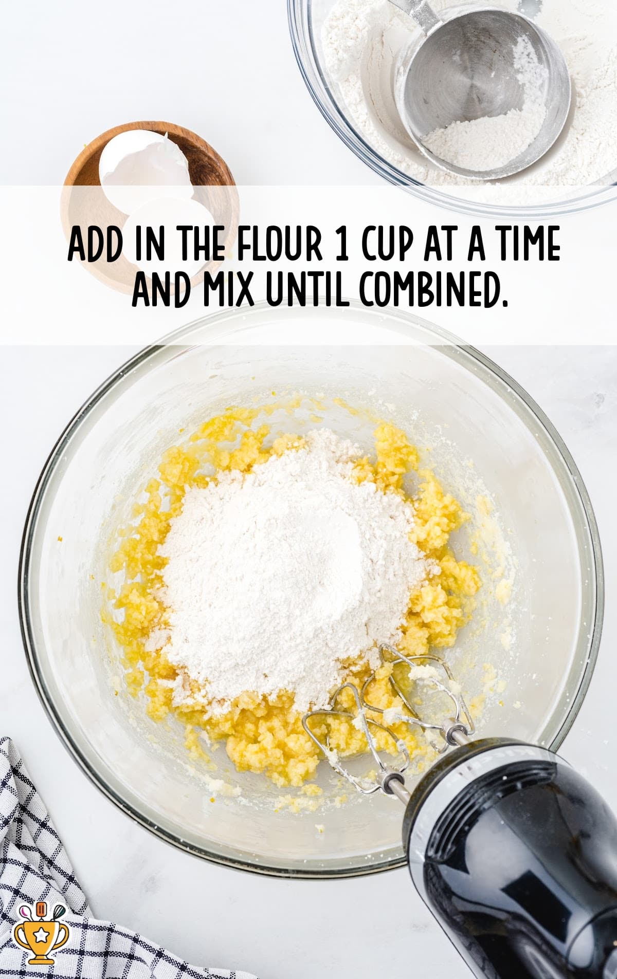 Flour added to the cookie dough mixture, mixing in stages with a hand mixer in a glass bowl.