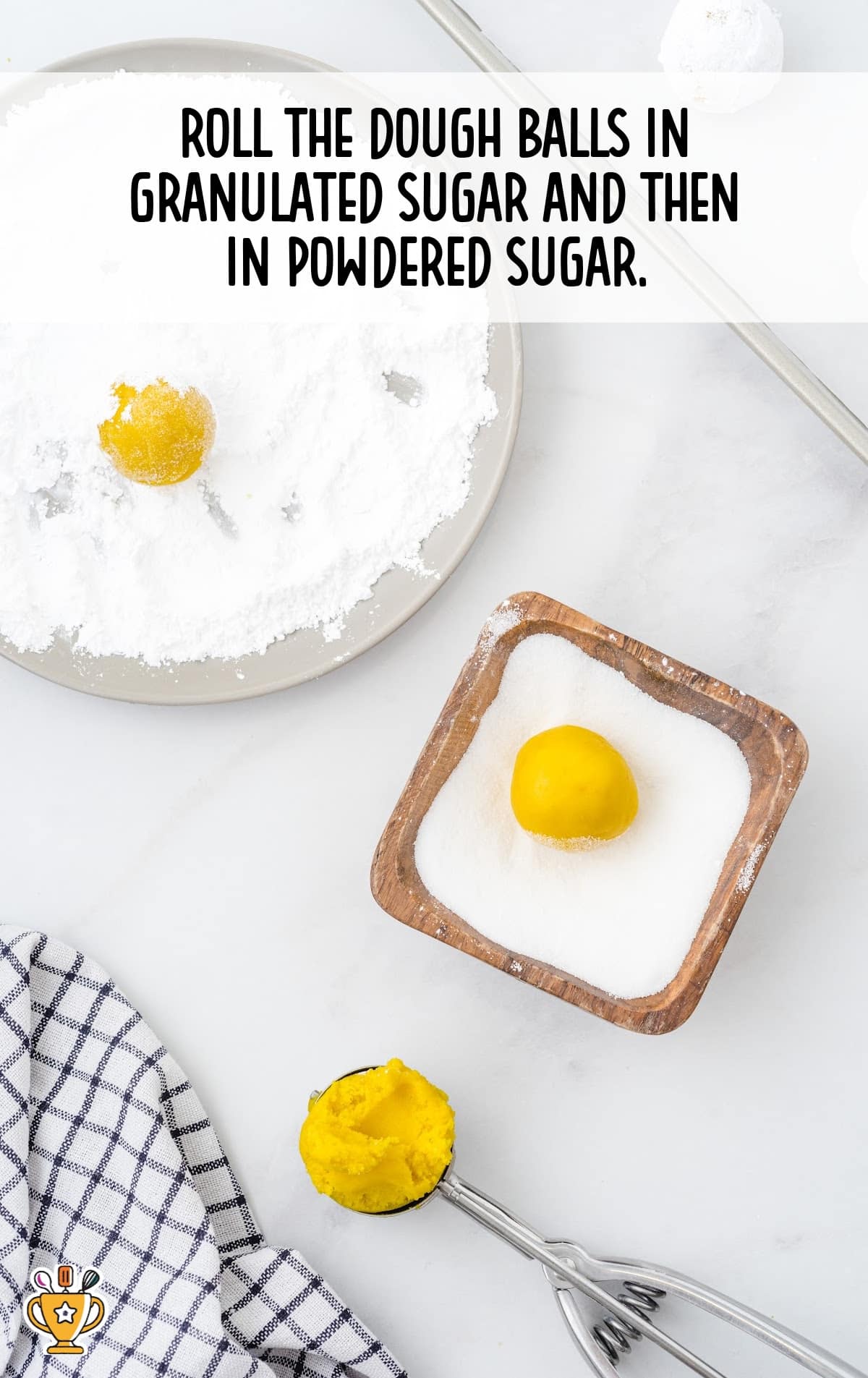 Yellow dough balls being rolled in granulated sugar and powdered sugar on two separate plates with a cookie scoop nearby.