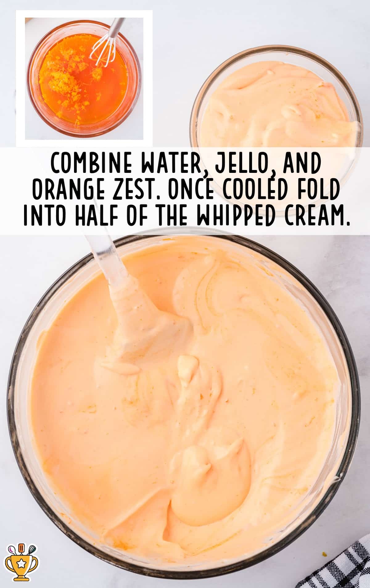 Bowl of light orange mixture with a spatula; small bowl of orange liquid with zest shown in the corner, demonstrating how to fold whipped cream into the Jello mix.