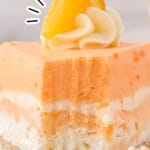 A vibrant slice of no-bake orange creamsicle cake on a plate with a bite taken out, showcasing its creamy layers and graham cracker crust.