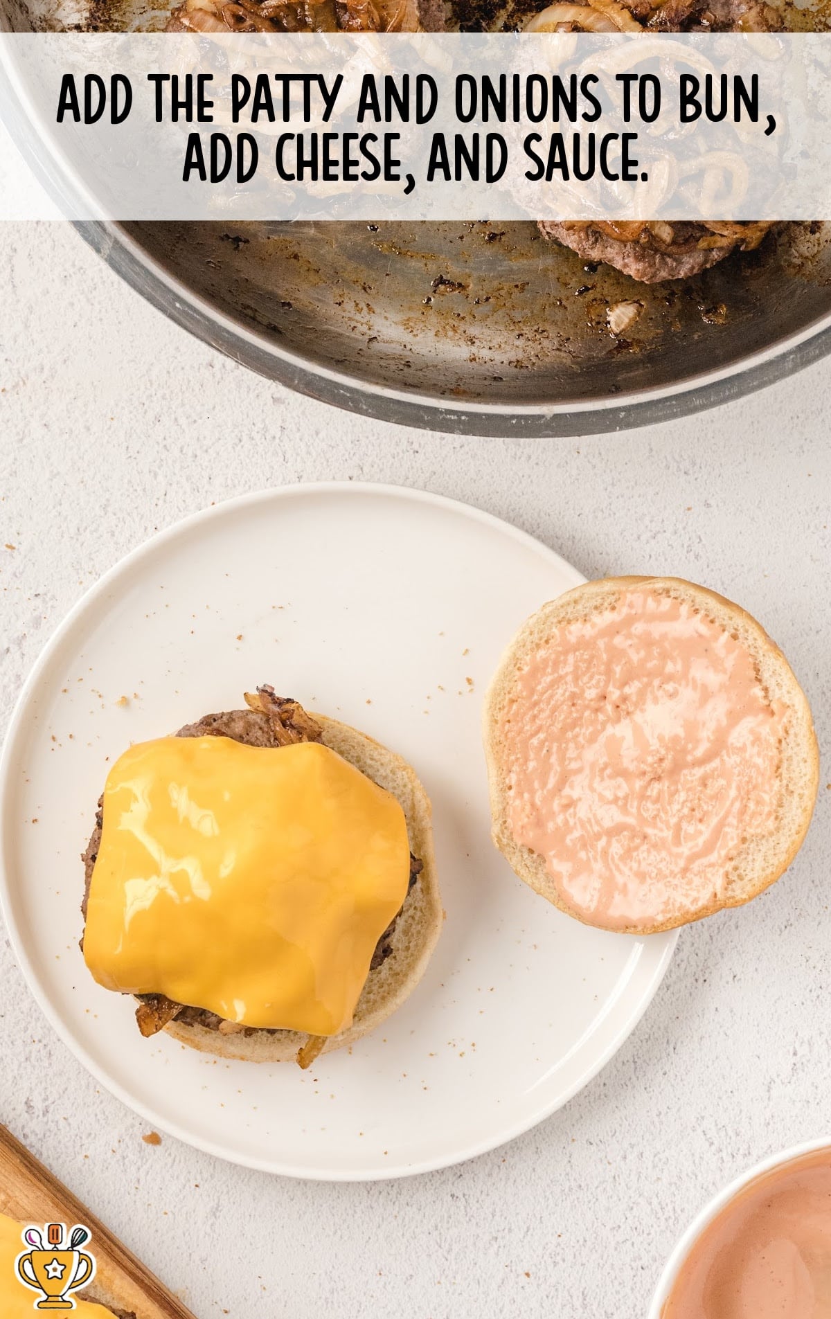 Open burger bun with a patty topped with melted cheese on one side and special sauce on the other, ready to be closed.
