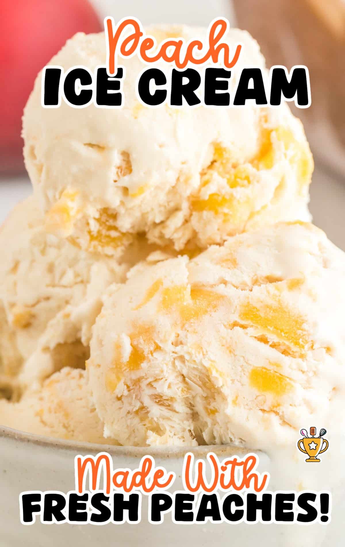 Zoomed-in view of peach ice cream scoops in a bowl with fresh peach chunks and creamy texture.