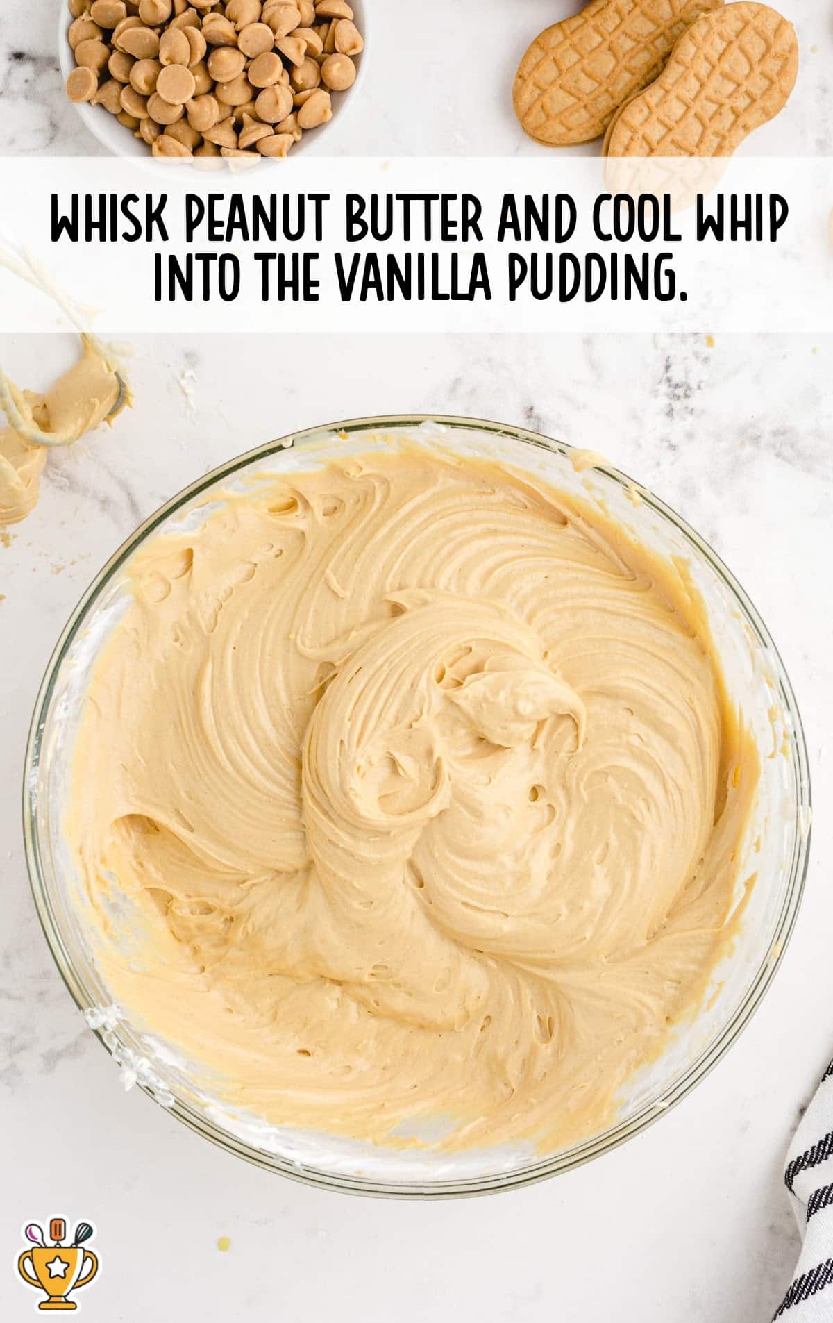 Large glass bowl of smooth, light brown peanut butter pudding mixture made by combining vanilla pudding, peanut butter, and whipped topping.