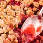 Tall pin graphic with a spoon in a pan of rhubarb strawberry crisp and bold text saying &ldquo;The Best Rhubarb Strawberry Crisp Recipe.&rdquo;