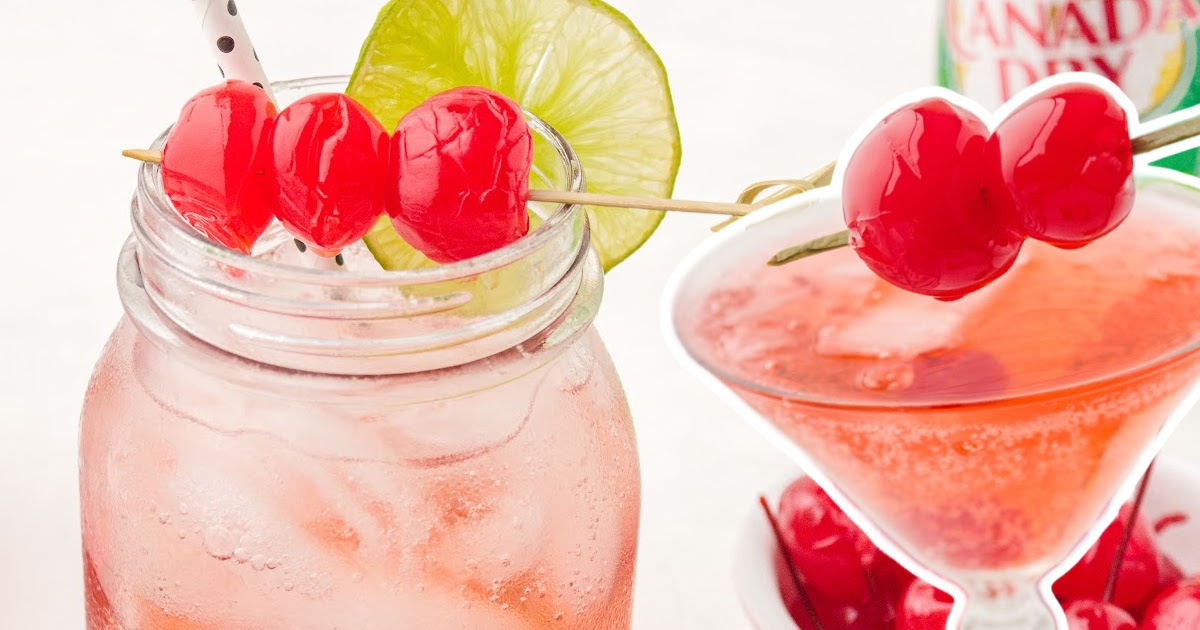 Crisp photo of a Shirley Temple in a mason jar with bubbles rising through the drink, garnished with cherries and a lime slice.