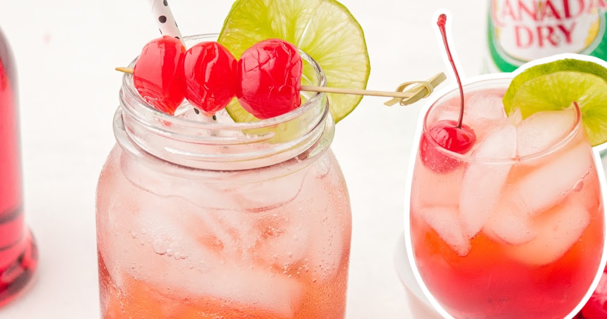 Mason jar filled with Shirley Temple mocktail, garnished with three maraschino cherries and a lime slice on the rim.