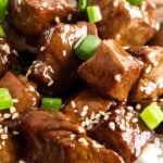 Closeup of teriyaki steak bites over white rice with sesame seeds, labeled "Teriyaki Steak Bites &ndash; Savory and So Delicious!"