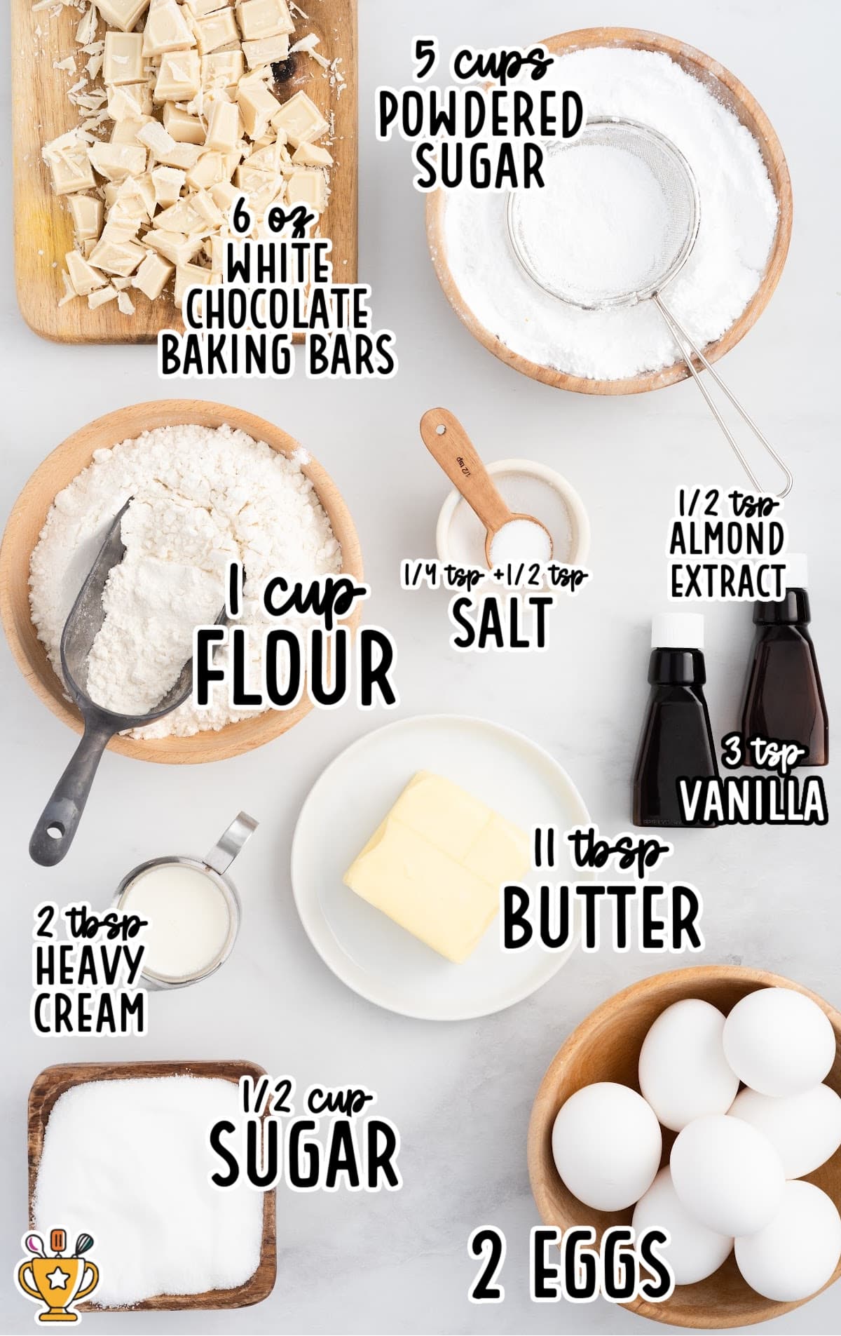 Flat lay of labeled vanilla brownie ingredients including white chocolate, flour, butter, sugar, eggs, and extracts on a white background.