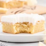 Flat lay image of vanilla brownie ingredients including flour, butter, white chocolate bars, sugar, eggs, and extracts arranged neatly on a white surface