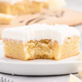 Flat lay image of vanilla brownie ingredients including flour, butter, white chocolate bars, sugar, eggs, and extracts arranged neatly on a white surface