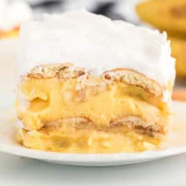 Clean, close-up image of a single banana pudding slice with visible creamy pudding and cookie layers, topped with fluffy whipped topping.