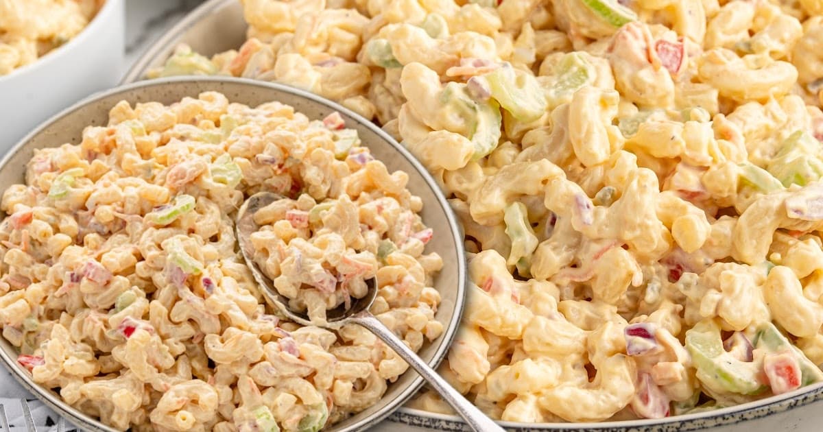 Two bowls of creamy macaroni salad side by side, each filled with tender pasta, celery, and red peppers.