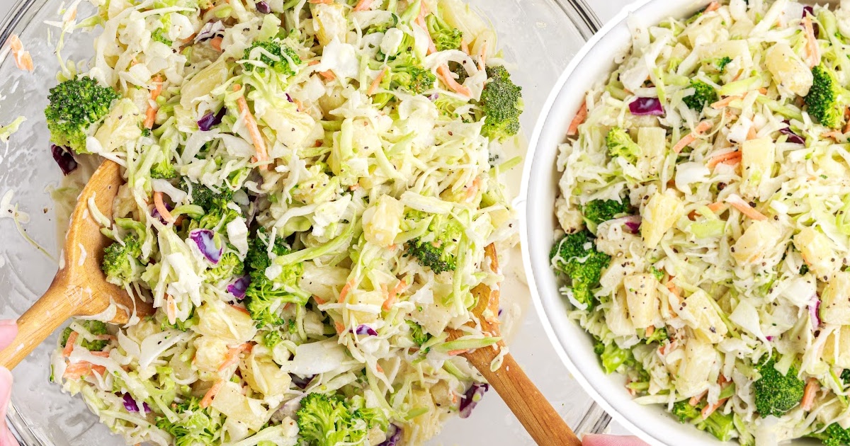 Hands mixing pineapple coleslaw with wooden spoons in a clear bowl, next to a finished bowl full of creamy coleslaw.