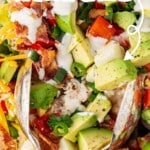 Overhead close-up of a vibrant layered chicken bacon ranch salad in a glass bowl, with avocado, bacon, eggs, tomatoes, shredded cheese, green onions, and ranch dressing. Bold text overlay reads &ldquo;Crack Layered Ranch Salad &ndash; Full of Bold Ranch Flavor!&rdquo; with branding from The Best Blog Recipes.