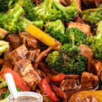 Vertical image of a vibrant stir fry with broccoli, red and yellow bell peppers, and chunks of chicken or pork coated in a glossy sauce. A jar of dark stir fry sauce with a spoon is featured in the corner. Text overlay reads “3 Ingredient Stir Fry Sauce – Seriously So Simple & Easy.”