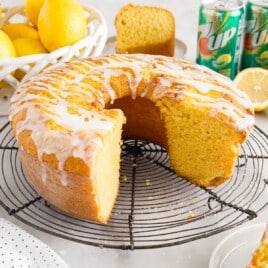 a 7Up Cake with a piece missing on a cooling rack
