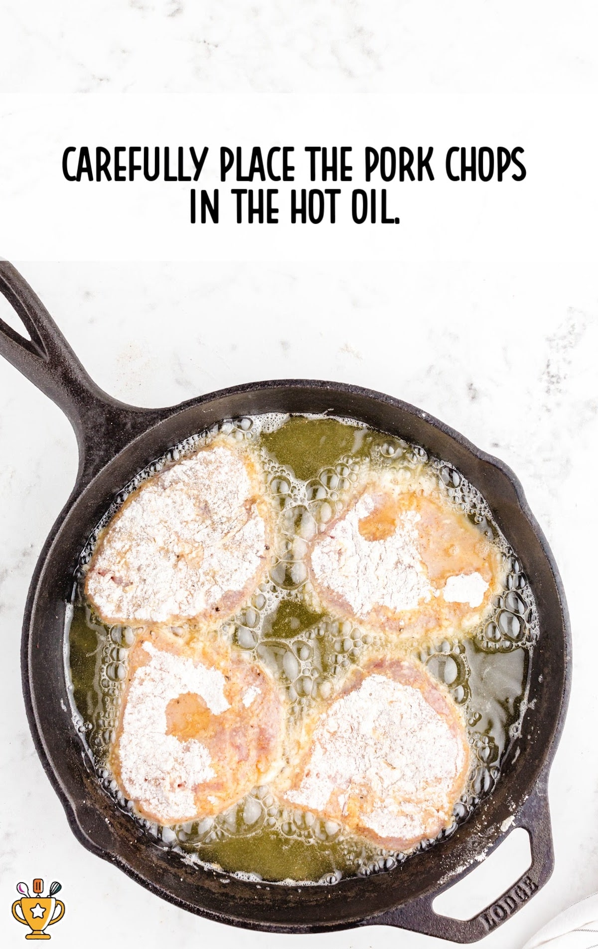 Pan-frying pork chops in hot oil in a cast-iron skillet, with sizzling bubbles around the crispy crust.