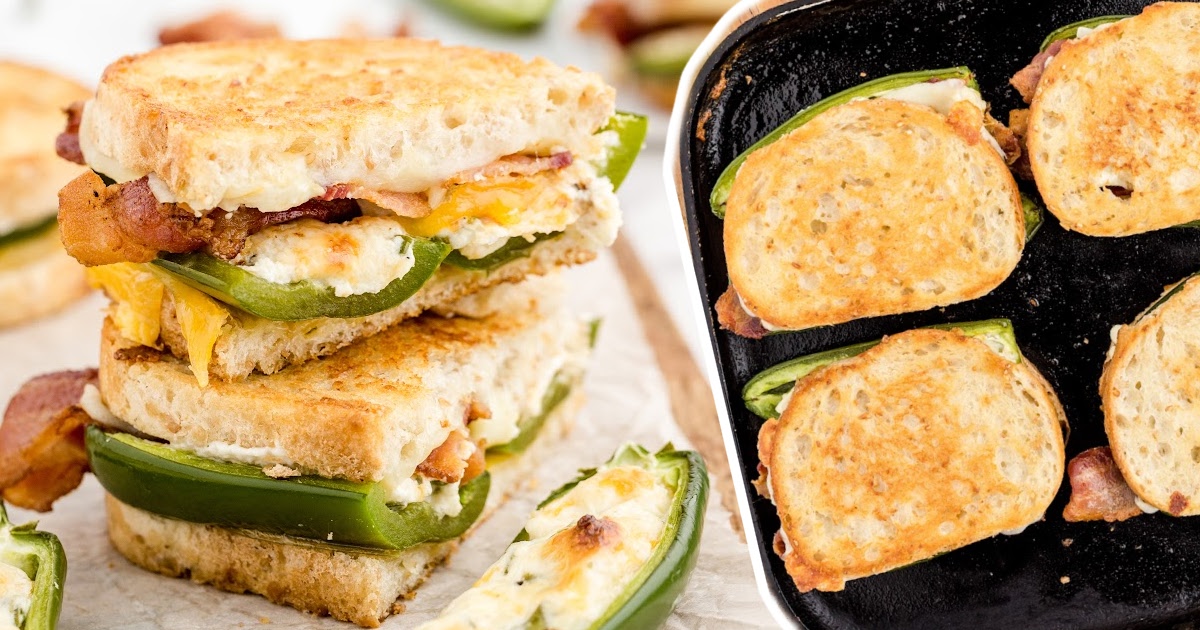 Sliced grilled cheese sandwich layered with jalapeño halves, bacon, and melted cheese, beside a skillet with four cooking sandwiches.