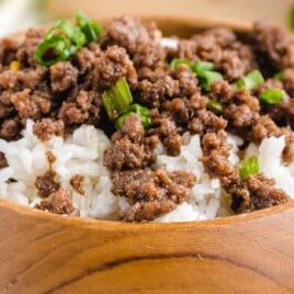 a close up photo of a wooden bowl served with rice and Korean Beef