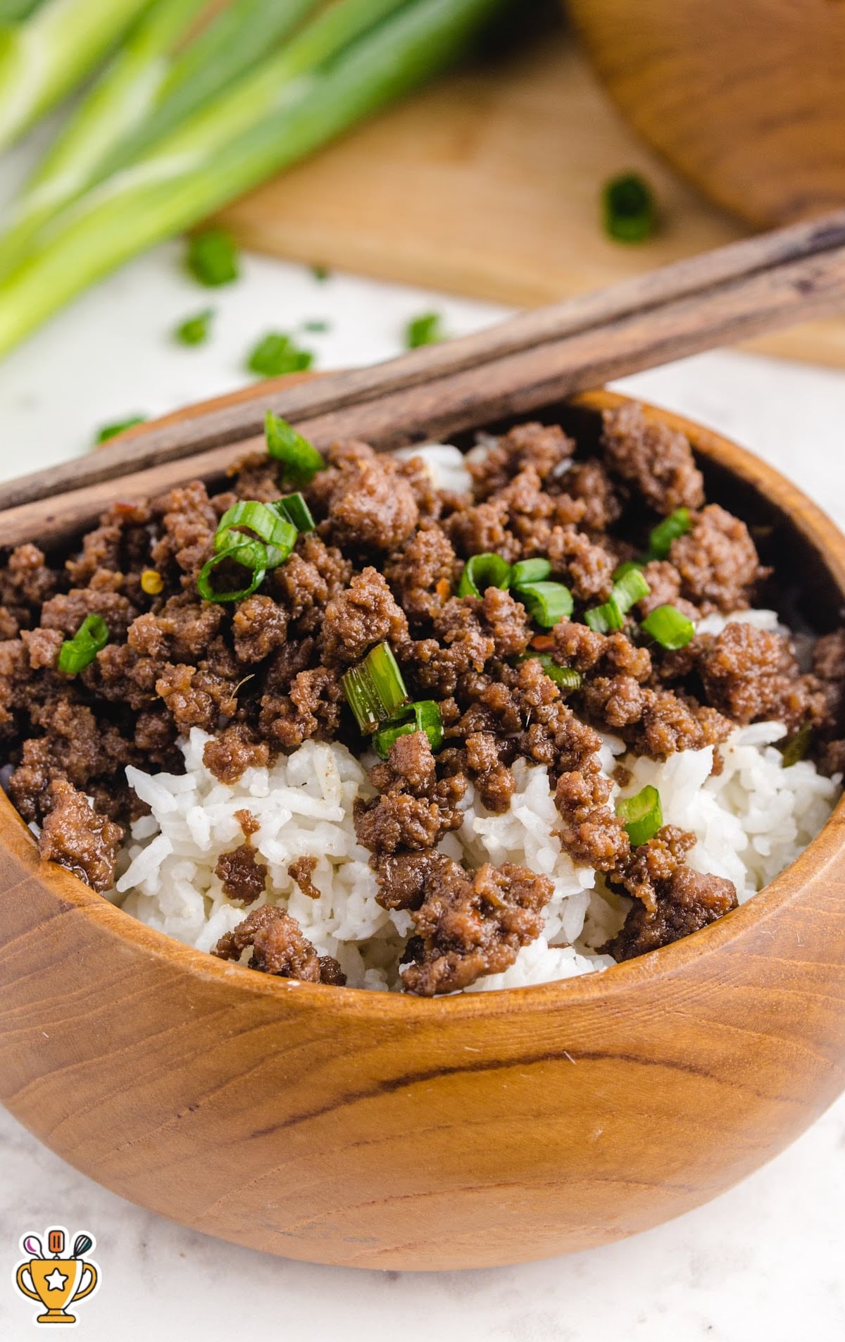 Korean Beef served with rice in a wooden bowl with two wooden chopsticks on it