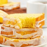 Three slices of lemon pound cake stacked neatly on a white plate, with icing glaze dripping down the sides