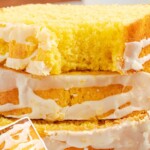 Three slices of lemon pound cake stacked neatly on a white plate, with icing glaze dripping down the sides