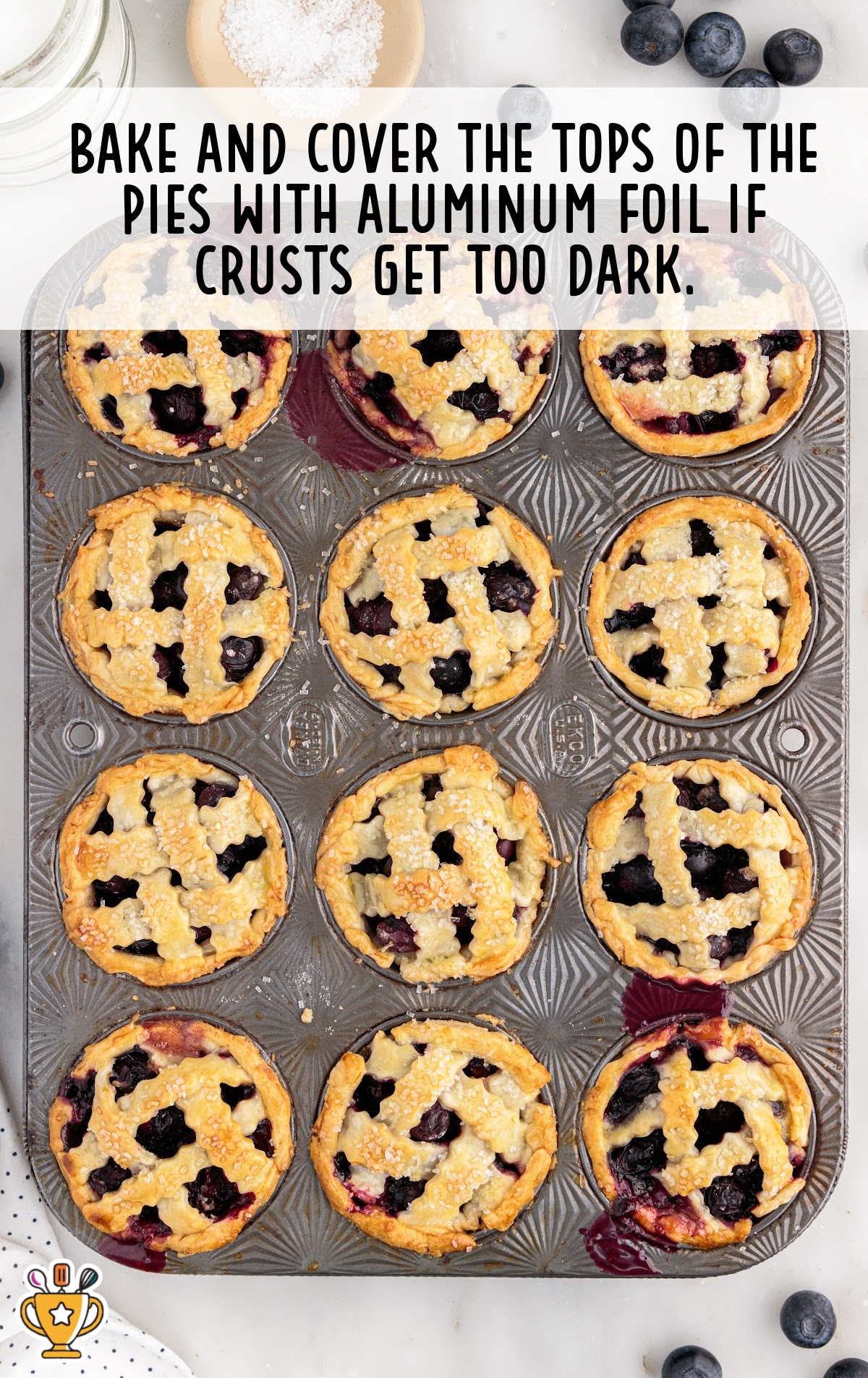 Golden brown mini blueberry pies baked in a muffin tin, with a tip suggesting to cover with foil if crusts brown too quickly.