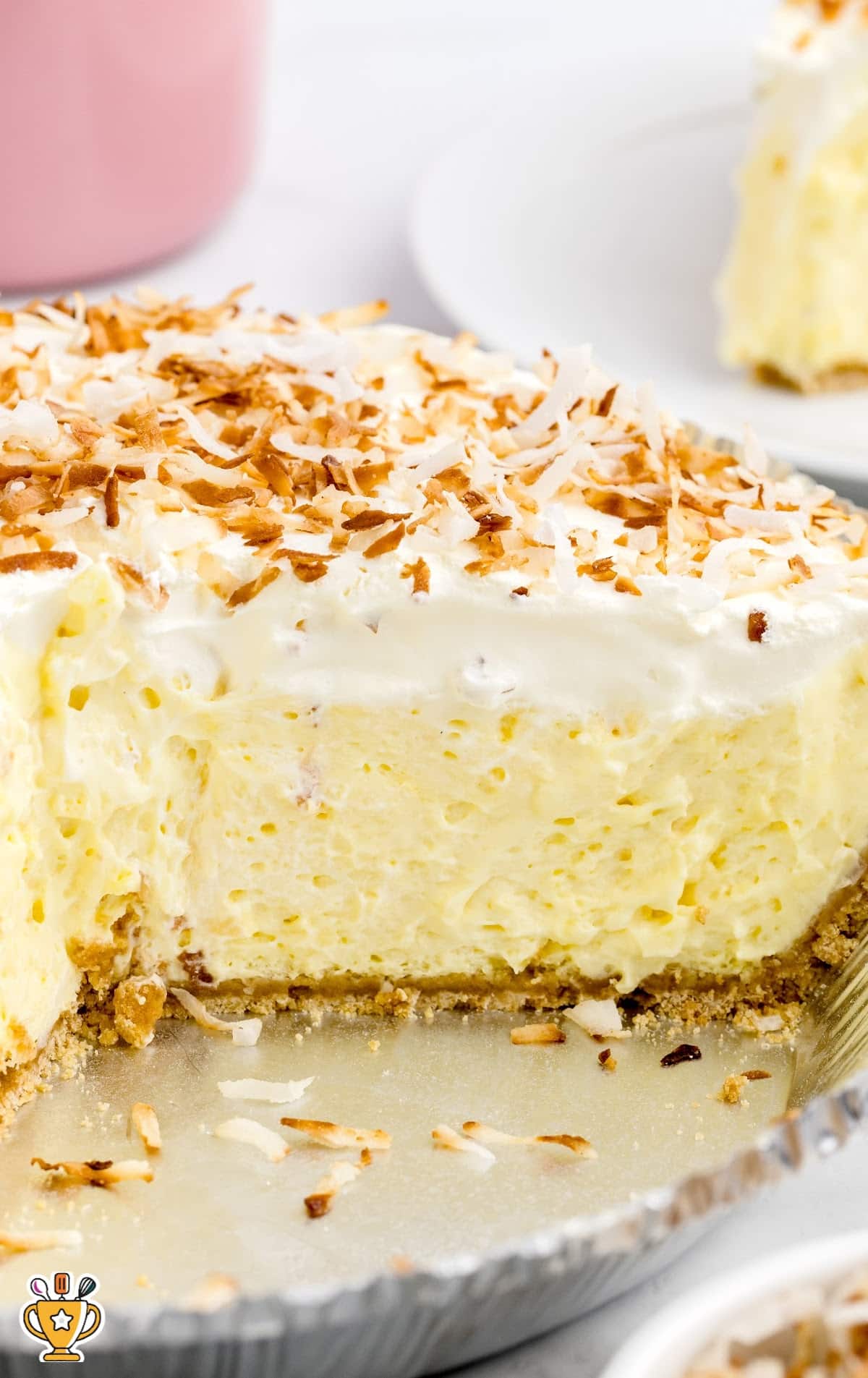 Zoomed-in shot of a cut-open coconut cream pie, showing fluffy filling and graham cracker crust with toasted coconut flakes.