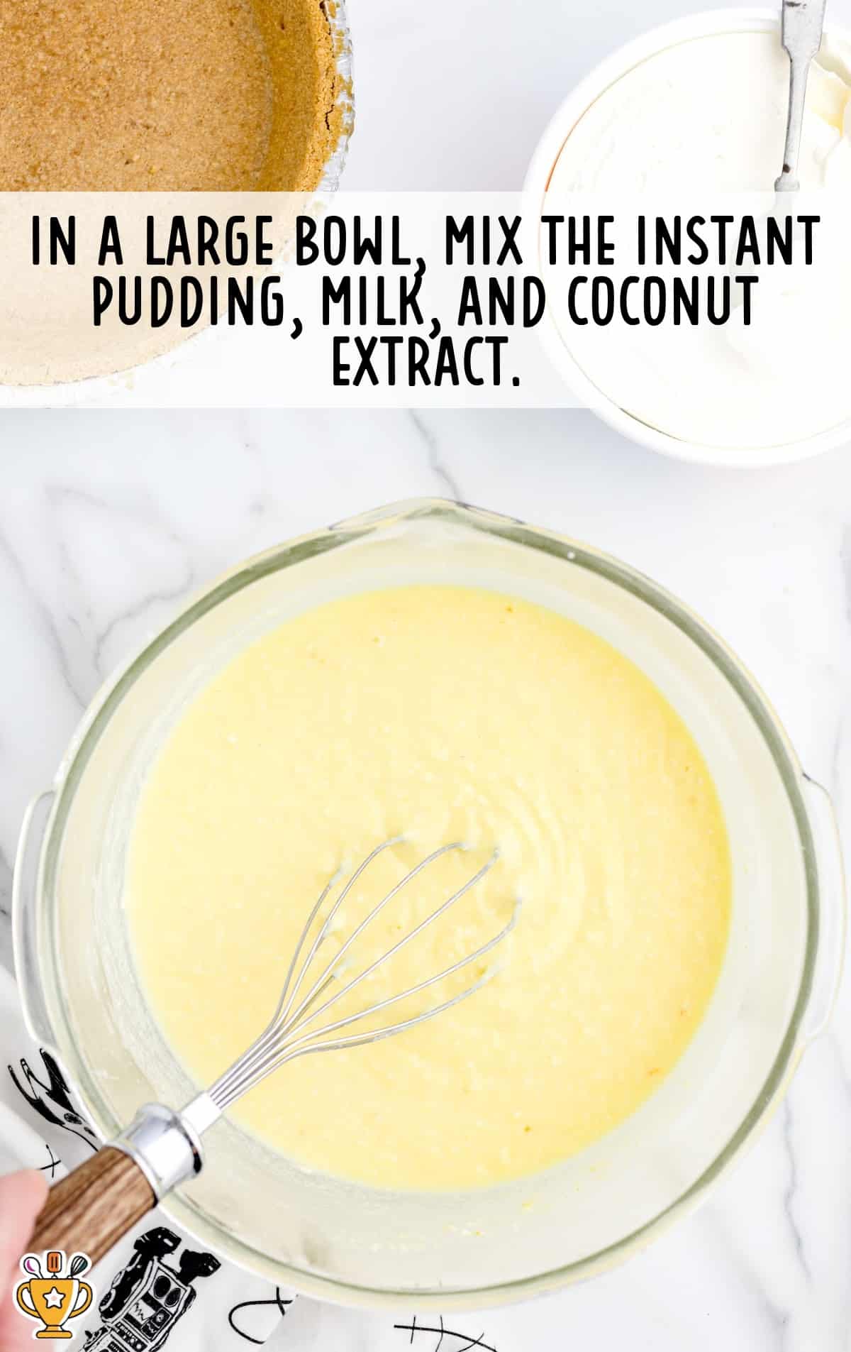 A large mixing bowl filled with yellow pudding mixture and a whisk, surrounded by a graham cracker crust and Cool Whip container.